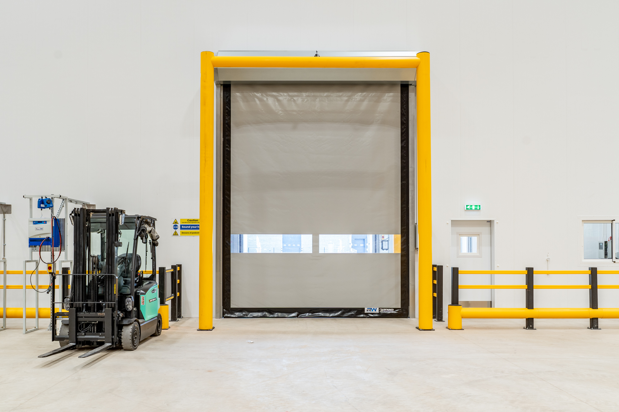 Rapid-roll door with yellow safety frame in temperature-controlled warehouse
